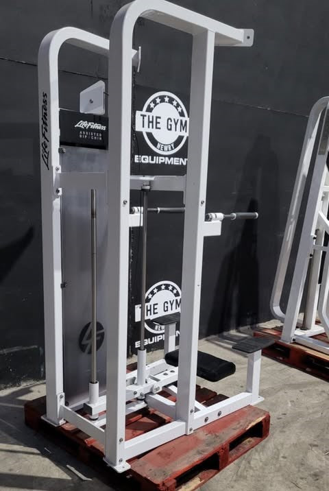 A white weight training machine with the text "The Gym" on it, standing on a wooden pallet.