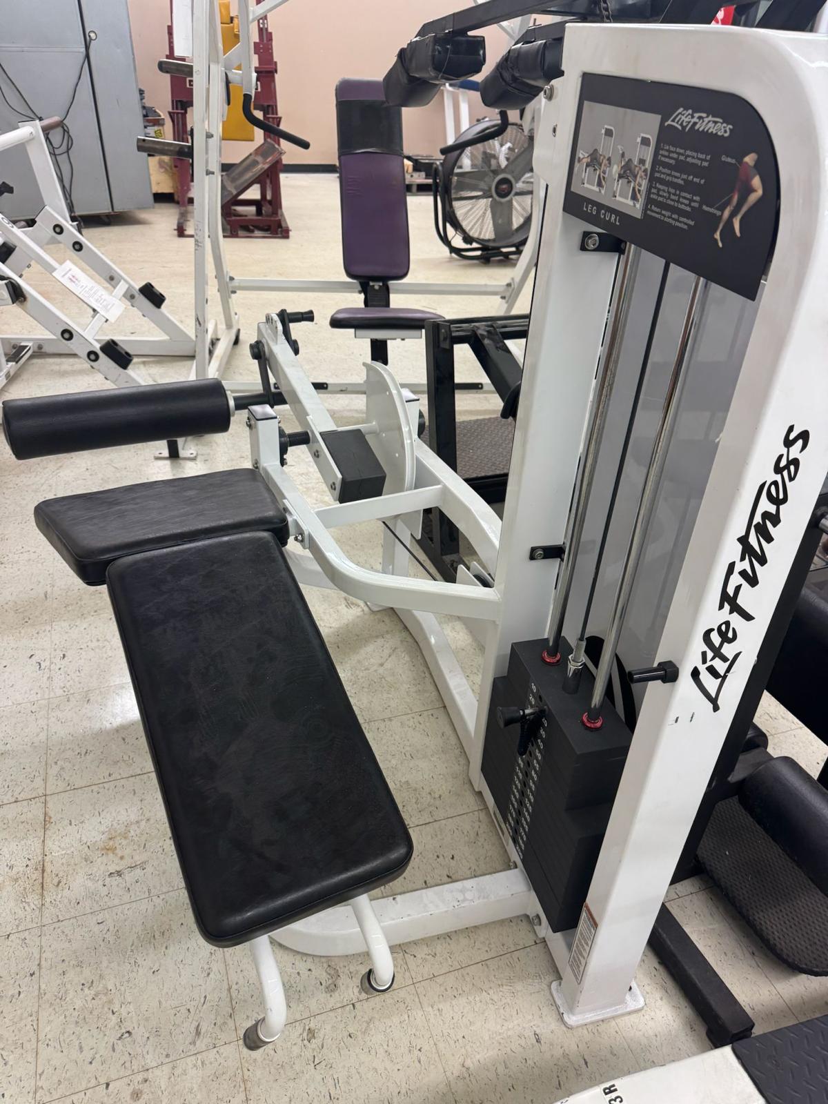 a well-equipped gym with various exercise machines, including a large weight machine and a bench press.