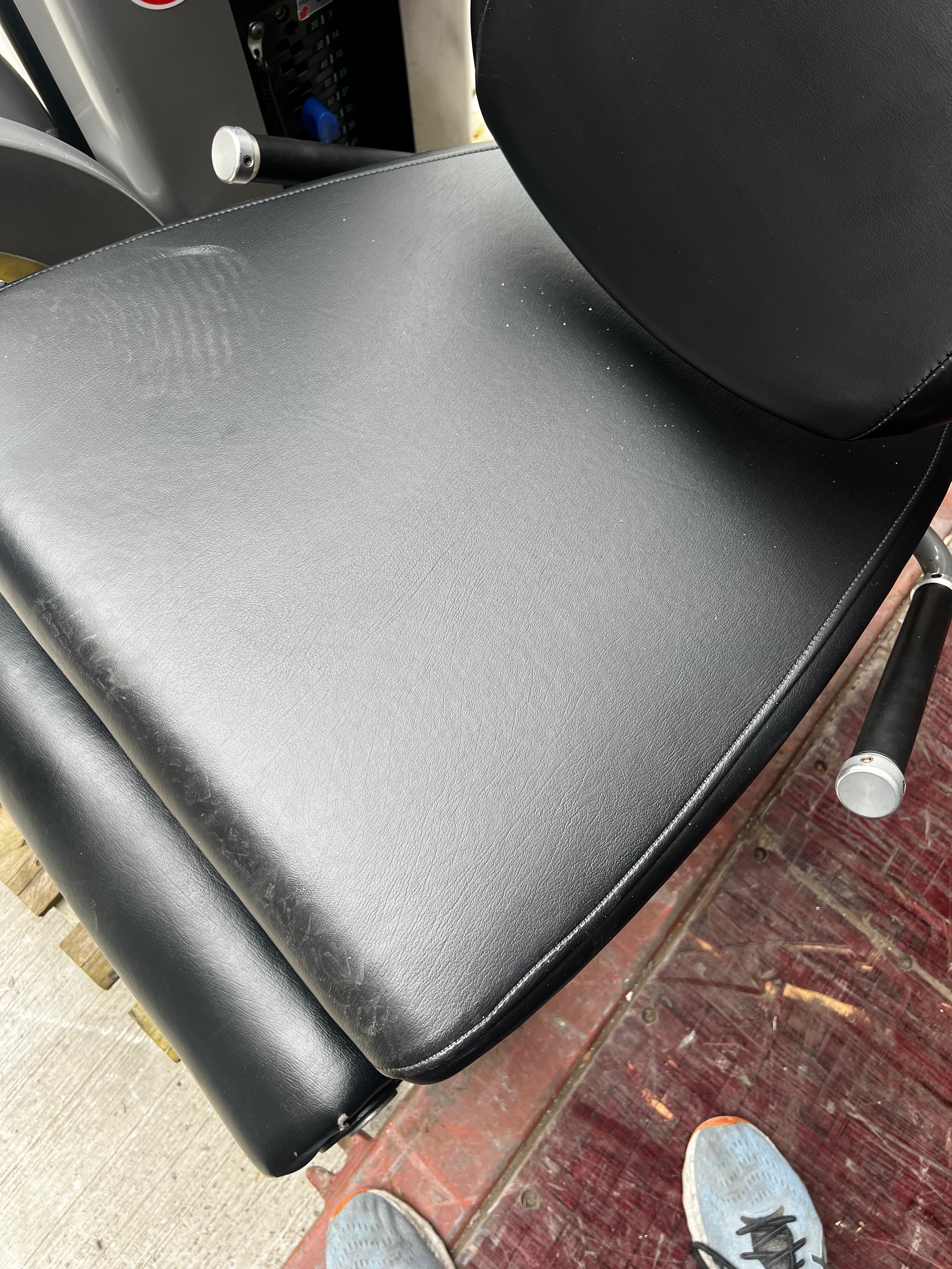 a black leather chair with a person's feet visible on the ground, suggesting the chair is placed outdoors.