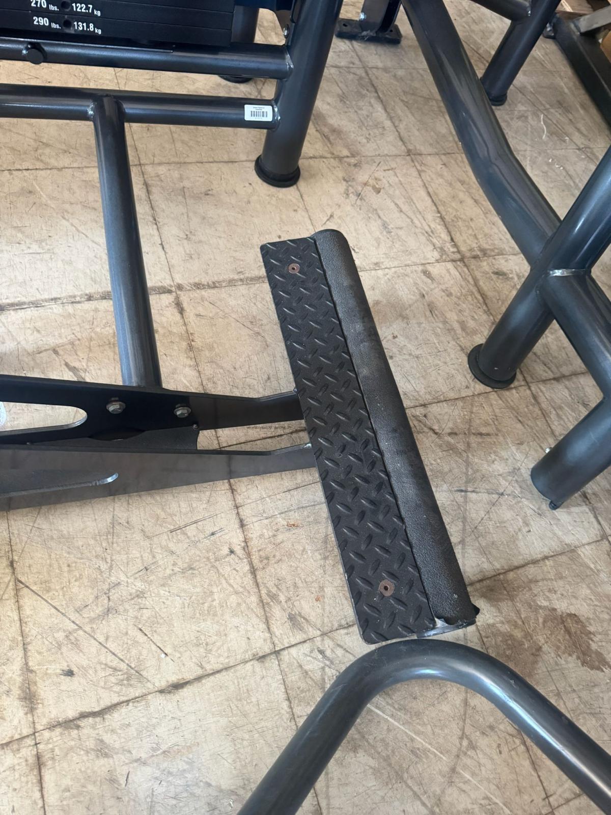 a close-up view of a black metal bar with a diamond-shaped plate attached to it, resting on a wooden floor.
