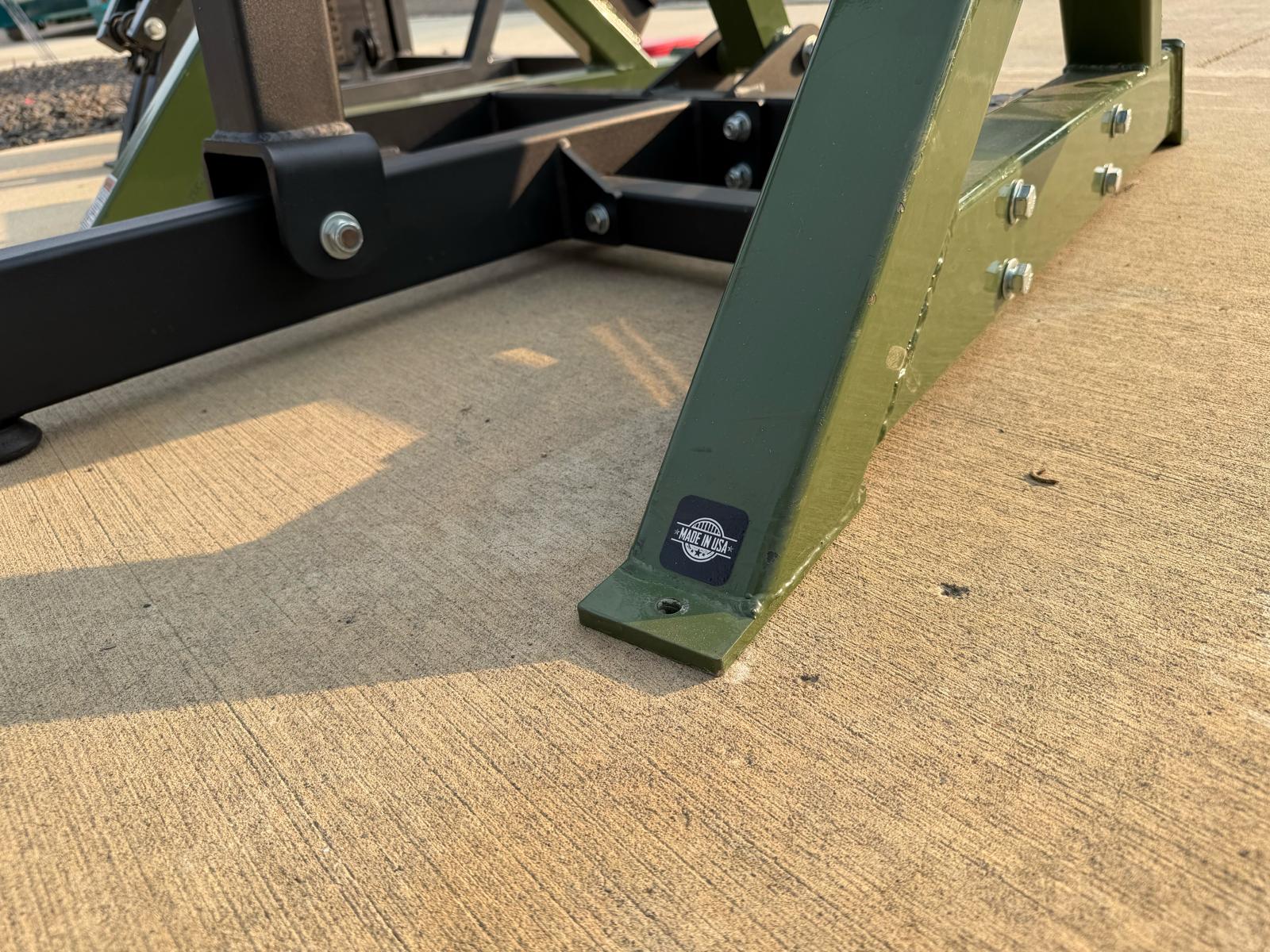 a close-up view of a green metal frame with a black metal bar attached to it, resting on a concrete surface.