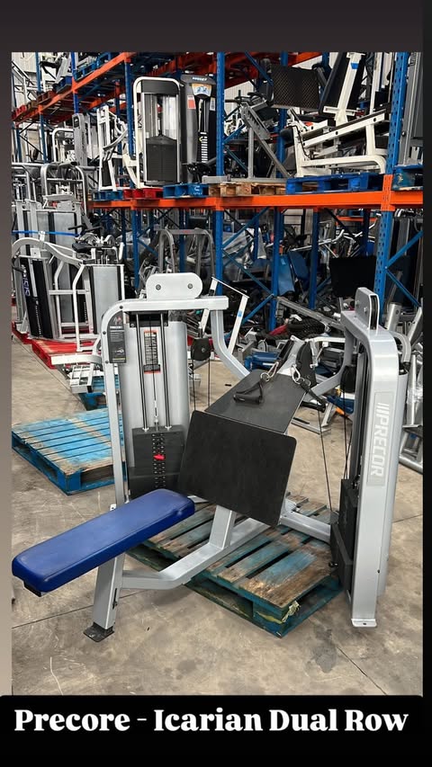 a collection of exercise equipment, including a dual row machine, in a warehouse setting.