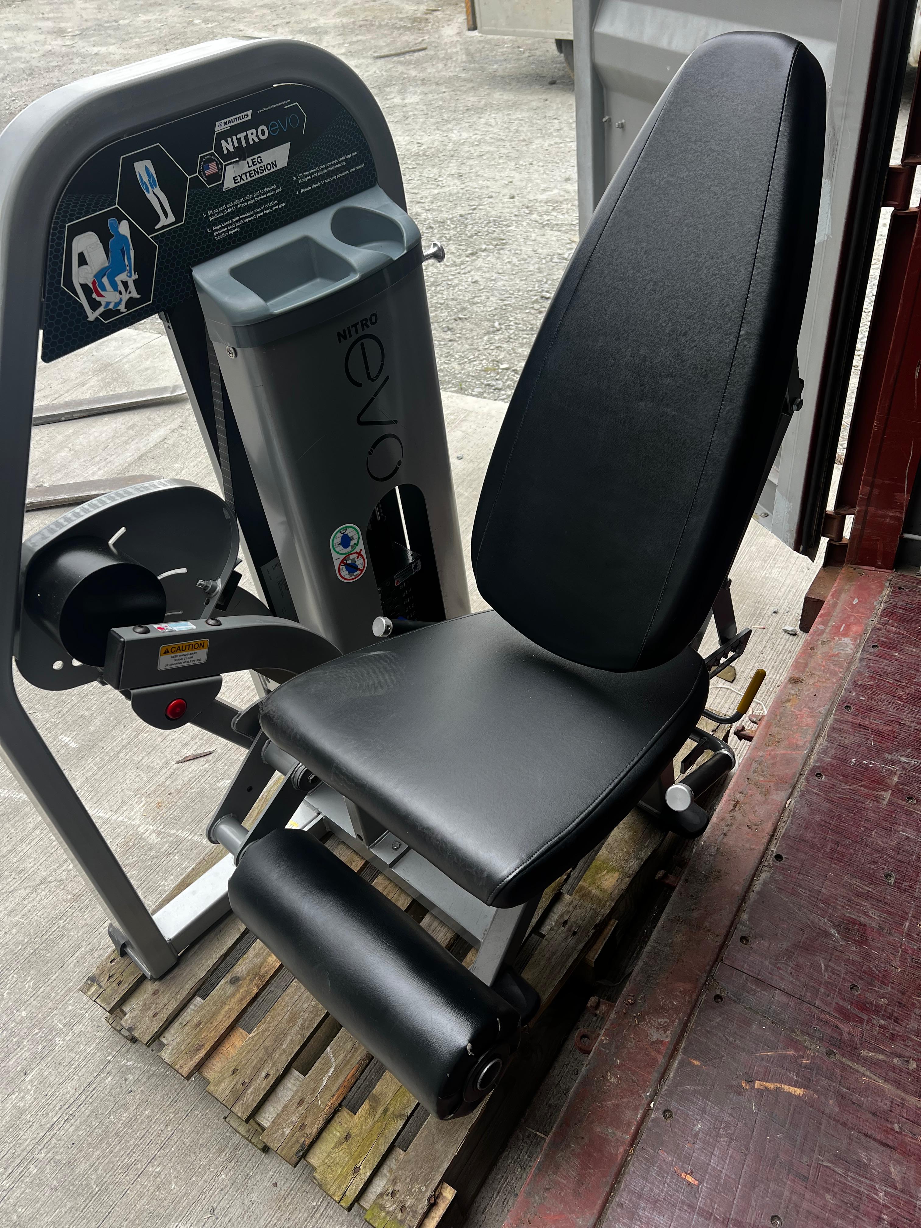 a black exercise machine with a gray base, placed on a wooden pallet.