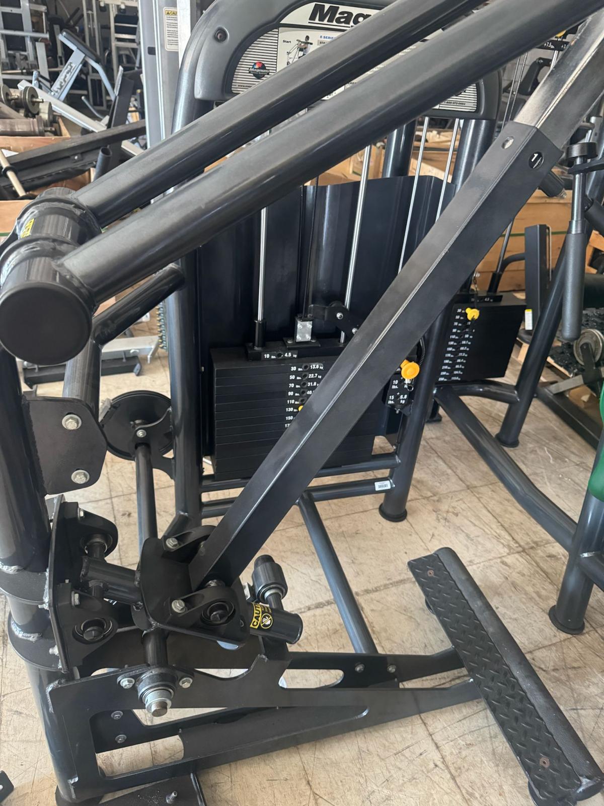 a weight training machine with various attachments and components, including a barbell and a weight plate.