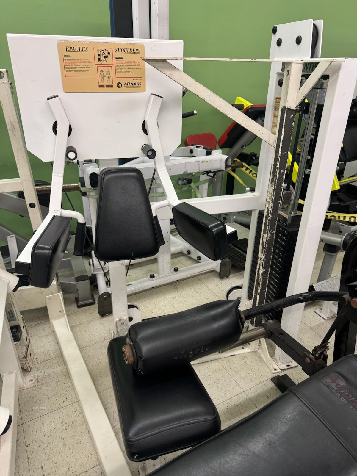 a well-equipped gym with various exercise machines, including a large weight machine and a leg press machine.