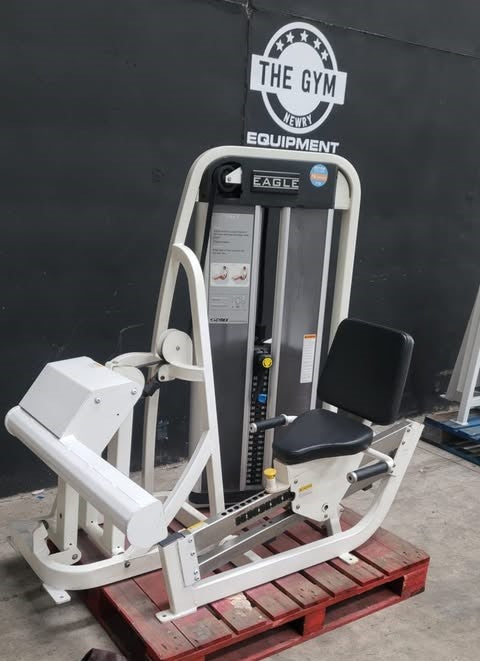 a weight training machine, specifically an Eagle brand leg press, placed on a wooden pallet in front of a gym wall.